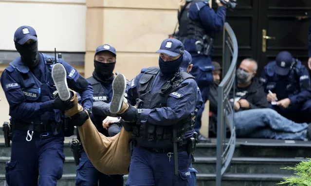 Police remove one of several protesters who had blocked the entrance of the country's constitutional court in an act of civil disobedience in Warsaw, Poland, on Monday August 30, 2021. The protest took place on the eve of an expected court ruling critical to the country's future relationship with the rest of the European Union. Judges of the Constitutional Tribunal are scheduled to convene on Tuesday to decide what has primacy – the central European nation's own constitution or the law of the 27-member bloc. (Photo by Czarek Sokolowski/AP Photo)