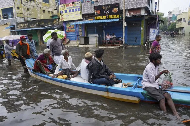 People travel on a boat in floodwaters on the outskirts of Chennai, India, Thursday, Nov. 10, 2021. Heavy rainfall will continue across Tamil Nadu state through November 11, 2021. (Photo by R. Parthibhan/AP Photo)