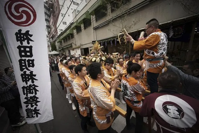 Carrying a portable shrine, on their shoulders, participants all clad in traditional happi coats, parade through precincts of the Kanda Myojin shrine during the annual summer festival in Tokyo, Saturday, May 9, 2015. (Photo by Eugene Hoshiko/AP Photo)