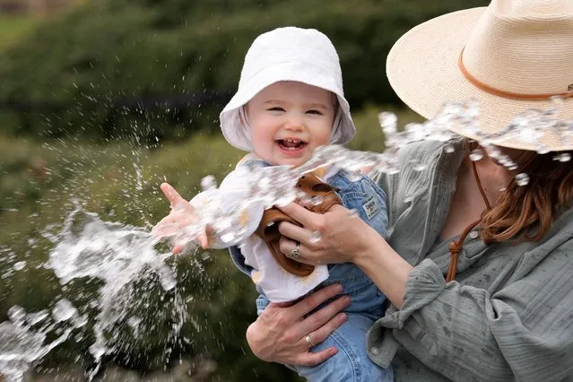 One year old Vivian Cain, left, is held by her mother Valeri Cain as they enjoy a water spray during warm water at the Dallas Arboretum and Botanical Garden in Dallas, Tuesday, February 27, 2024. (Photo by L.M. Otero/AP Photo)