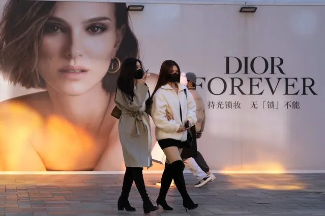 Women wearing masks walk past an ad for Dior at a mall in Beijing, China, Thursday, November 25, 2021. A renowned Chinese fashion photographer has apologized for her past work after online critics called it insulting to the Chinese people and fashion house Dior removed one of her photos from a show in Shanghai. (Photo by Ng Han Guan/AP Photo)