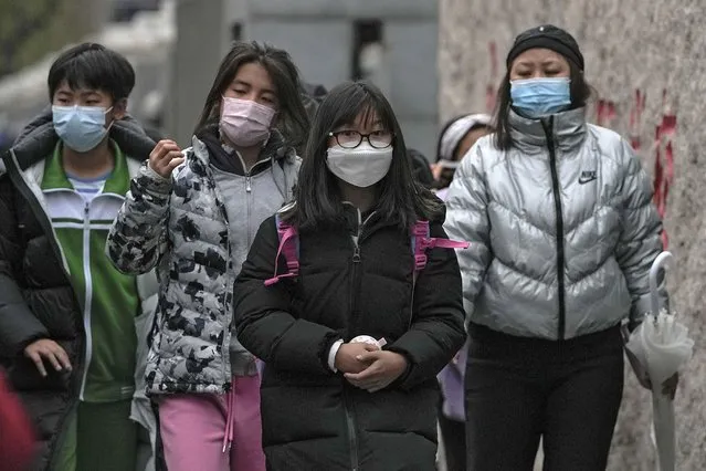 Students wearing face masks to help curb the spread of the coronavirus leave their school after classes in Beijing, Monday, November 29, 2021. Despite the global worry, scientists caution that it's still unclear whether the omicron COVID-19 variant is more dangerous than other versions of the virus that has killed more than 5 million people. Some countries are continuing with previous plans to loosen restrictions, with signs of reopening in Malaysia, Singapore and New Zealand. (Photo by Andy Wong/AP Photo)