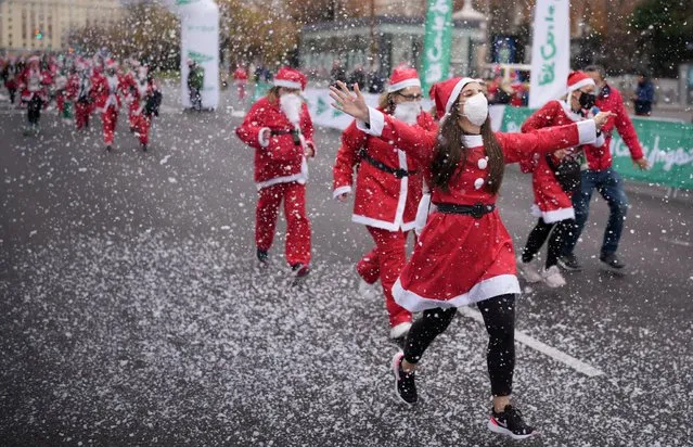 People wearing Santa Claus outfits take part in a charity race to collect funds to help victims of the Cumbre Vieja volcano eruption, in Madrid, Spain on December 19, 2021. (Photo by Juan Medina/Reuters)