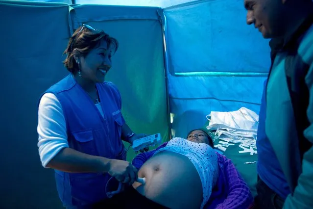 Obstetrician Martina Mantilla listens to the heartbeat of Carmen Rosas' baby during a prenatal check, inside a tent converted into a makeshift medical office, in Surcubamba, Peru, Thursday, May 21, 2015. (Photo by Rodrigo Abd/AP Photo)