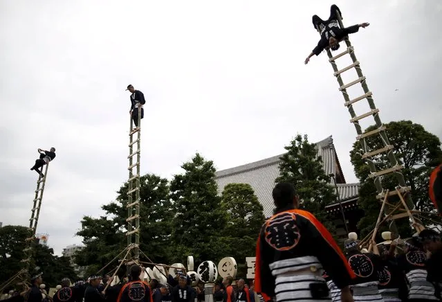 Men wearing costume of traditional firefighters perform  acrobatic stunts atop a bamboo ladder following a memorial service for firefighters at Sensoji temple in Tokyo's downtown of Asakusa May 25, 2015. (Photo by Issei Kato/Reuters)