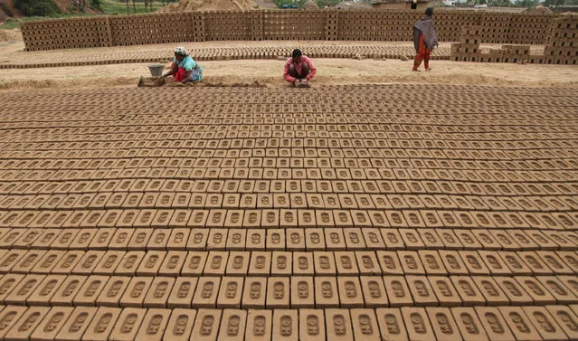 Indian laborers work at a brick kiln on the outskirts of Jammu, India, Tuesday, April.19, 2016. Brick making is an unorganized industry, generally confined to rural and semi-urban areas and is a large employment-generating industry in India. The laborers usually work for 12-14 hours a day earning 200 rupees ($2.5) per day. (Photo by Channi Anand/AP Photo)