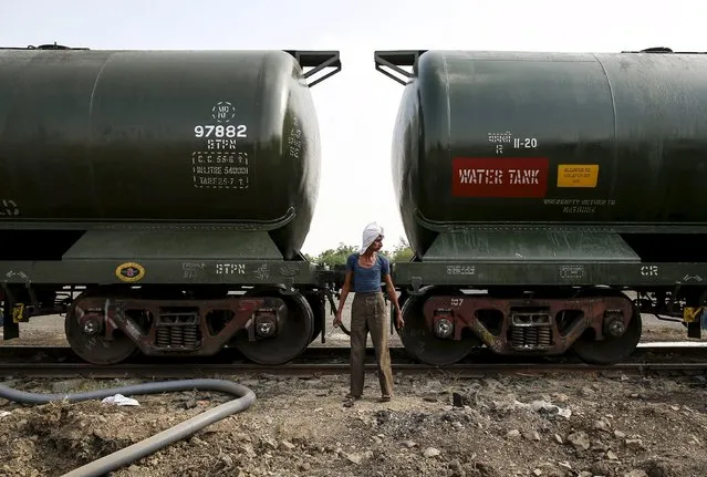 A worker stands in front of a tanker wagon carrying water at a railway station in Latur, India, April 16, 2016. (Photo by Danish Siddiqui/Reuters)