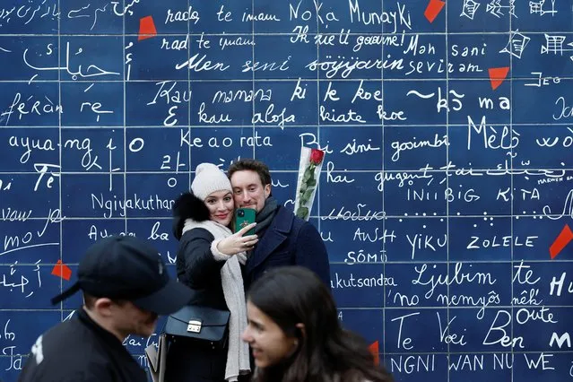 A couple takes a picture in front of the “Wall of Love” in the Jehan Rictus garden square in Paris, France, February 14, 2022. (Photo by Benoit Tessier/Reuters)
