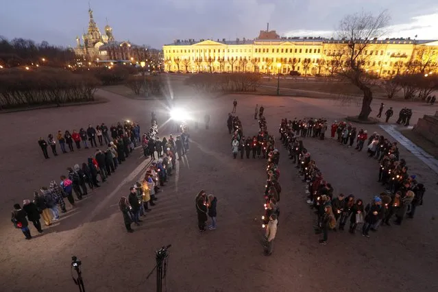 People form digits of the time of the subway bombing in memory of victims of the tragic event, on Marsovo Polye in St.Petersburg, Russia, Wednesday, April 5, 2017. A bomb blast tore through a subway train under Russia's second-largest city on Monday, killing several people and wounding more. (Photo by Dmitri Lovetsky/AP Photo)