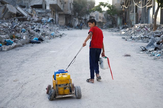 A Palestinian child pulls water containers in southern Gaza City, in the Gaza Strip on June 3, 2024. (Photo by Mohammed Salem/Reuters)