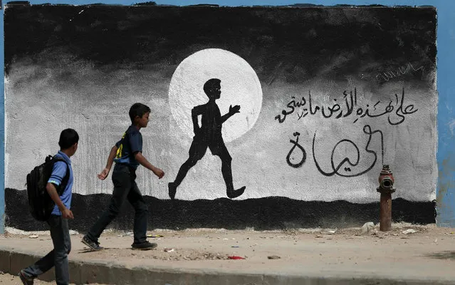 Two Palestinian schoolboys walk past a graffiti painted on a wall of the United Nations school of Beit Hanun, in the northern Gaza Strip, on May 9, 2016. (Photo by Thomas Coex/AFP Photo)