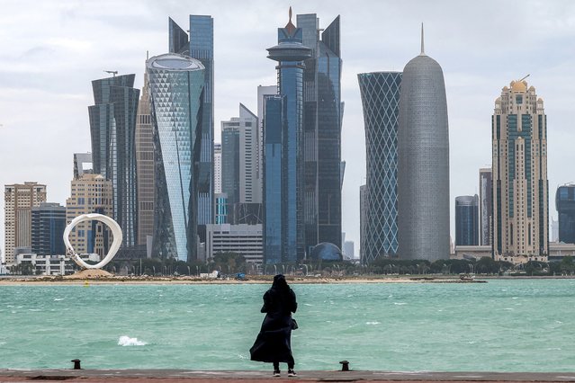A woman stands by the waterfront at the Doha corniche facing the high-rise buildings in the West Bay district on April 16, 2024. (Photo by Karim Jaafar/AFP Photo)
