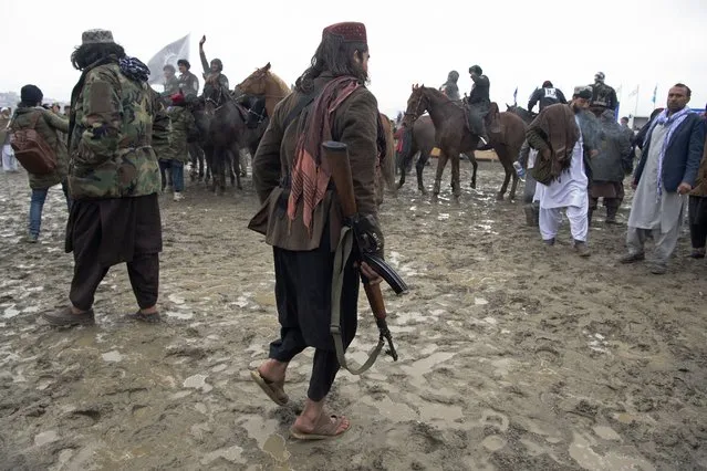 Taliban fighters stand near horsemen from Kandahar and Kunduz teams during the final of Afghanistan's Buzkashi League in Kabul on March 6, 2022. (Photo by Wakil Kohsar/AFP Photo)