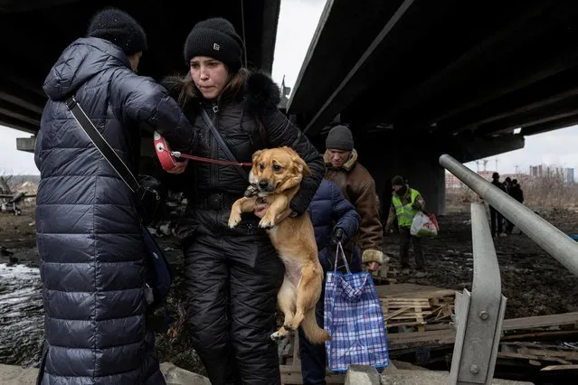 A woman carries her dog during an evacuation, as Russia's invasion of Ukraine continues, in the town of Irpin outside Kyiv, Ukraine, March 13, 2022. (Photo by Marko Djurica/Reuters)