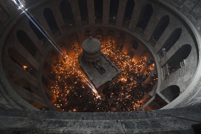 Christian pilgrims hold candles during the Holy Fire ceremony, a day before Easter, at the Church of the Holy Sepulcher, where many Christians believe Jesus was crucified, buried and resurrected, in Jerusalem's Old City, Saturday, April 15, 2023. (Photo by Tsafrir Abayov/AP Photo)