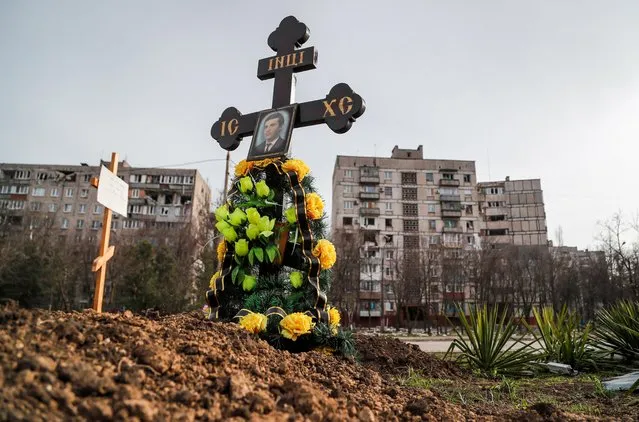 Graves of civilians killed during Ukraine-Russia conflict are seen next to apartment buildings in the southern port city of Mariupol, Ukraine on April 10, 2022. (Photo by Alexander Ermochenko/Reuters)