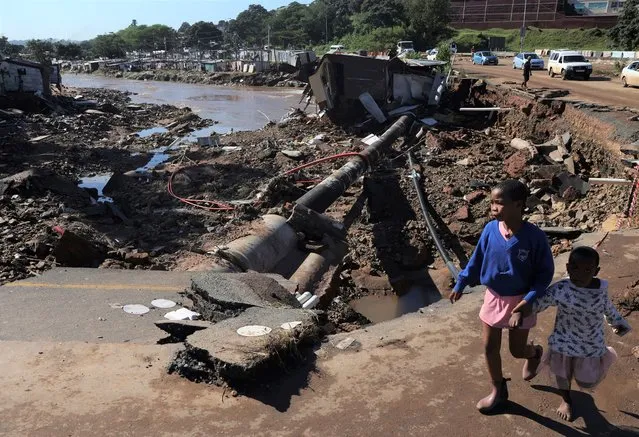 Children walk on damaged road at an informal settlement in Durban, South Africa, Thursday, April 14, 2022. Heavy rains and flooding have killed at least 341 people in South Africa's eastern KwaZulu-Natal province, including the city of Durban, and more rainstorms are forecast in the coming days. (Photo by AP Photo/Stringer)