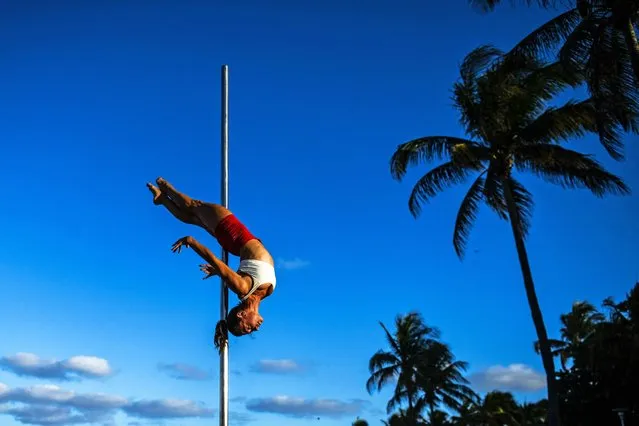 Nataliya Nomada practices pole acrobatics on the beach in Miami Beach, Florida on April 26, 2022. (Photo by Chandan Khanna/AFP Photo)