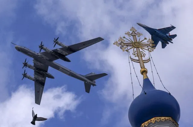 A Russian Su-35S combat aircraft and a Tu-95ms strategic bomber fly in formation above a church during a rehearsal for the flypast, which is part of a military parade marking the anniversary of the victory over Nazi Germany in World War Two, in Moscow, Russia on May 4, 2022. (Photo by Maxim Shemetov/Reuters)