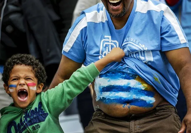 A young boy shows off Uruguay's flag on a man's stomach before the group D World Cup soccer match between Uruguay and England at the Itaquerao Stadium in Sao Paulo, Brazil. (Photo by Felipe Dana/Associated Press)