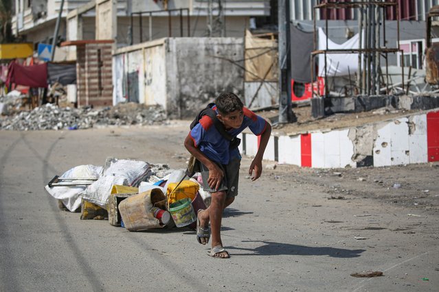 A Palestinian youth pulls salvaged items in Deir al-Balah in the central Gaza Strip on August 27, 2024, amid the ongoing conflict between Israel and the Palestinian Hamas movement. (Photo by Eyad Baba/AFP Photo)