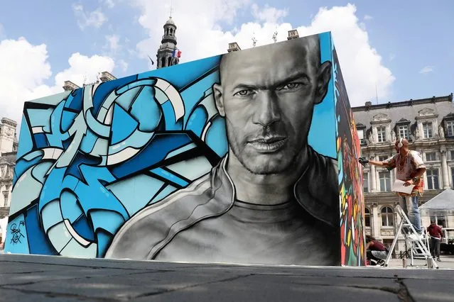 A painting of Real Madrid's French coach and former footballer Zinedine Zidane is pictured as an artist paints famous football players for an exhibition in front of the Hotel de Ville city hall in Paris on June 7, 2016, ahead of the start of the Euro 2016 football tournament. (Photo by Kenzo Tribouillard/AFP Photo)