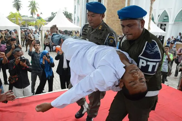 An Indonesian man faints after he was whipped in public on charges of engaging in sexual relations, in Aceh Timur on December 5, 2019. Two Indonesian men and a woman were whipped in Indonesia's Aceh province after they were found guilty of having pre-marital s*x, a serious crime under under the conservative region's Islamic law. (Photo by Cek Mad/AFP Photo)