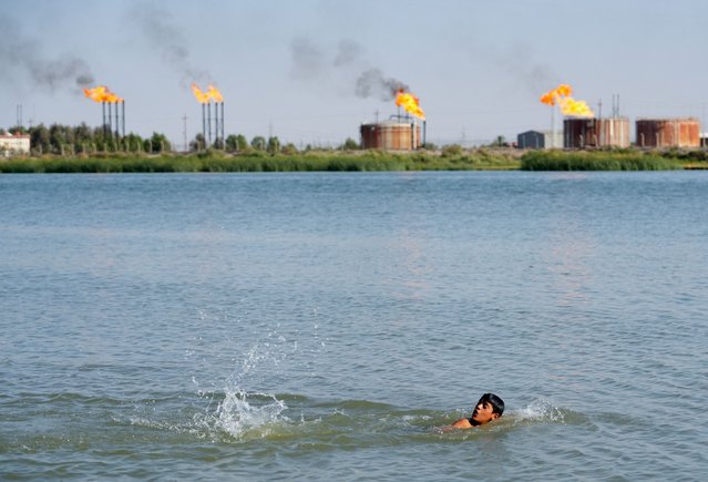 A boy swims to cool off amid high temperatures near Nahr Bin Umar oil field, in Basra, Iraq on June 30, 2024. (Photo by Mohammed Aty/Reuters)