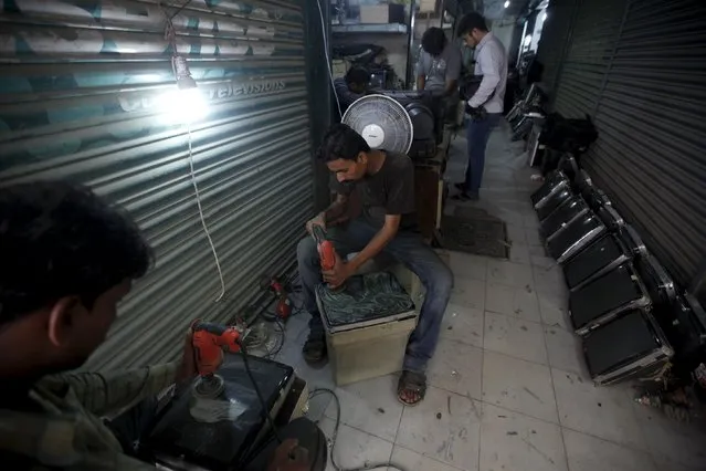 Workmen polish the screens of computer monitors to fit them into homemade television sets at a market in Karachi, Pakistan, July 29, 2015. (Photo by Akhtar Soomro/Reuters)