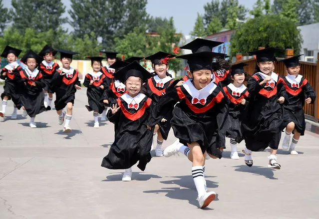 Children in gowns and mortarboards run with smiles during their kindergarten graduation ceremony in a kindergarten in Handan, Hebei province, China June 20, 2017. (Photo by Reuters/China Daily)