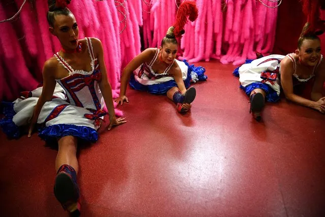 Dancers warm up in the wings before performing in a full-dress rehearsal at the Moulin Rouge in Paris on September 8, 2021, two days ahead of the reopening of the cabaret following an 18-month closure amid the COVID-19 pandemic. Closed for a year and a half due to the pandemic, the Moulin Rouge and Le Lido, emblems of the crazy Parisian nights since 1889, are finally reopening. (Photo by Christophe Archambault/AFP Photo)