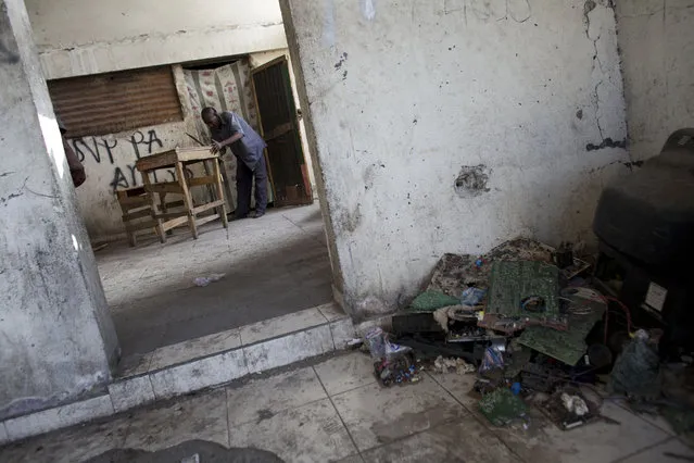 In this June 29, 2015 photo, carpenter Camen Innocent builds a market stall with a built-in seat for a client, outside his room in an earthquake-damaged government building in central Port-au-Prince, Haiti. Innocent, 57, says he was the first person to take up residence in the abandoned building after the quake. For the last several years, the residents have lived here largely undisturbed. But they know the government could return to reclaim the building at any time, leaving them on the street once again. (Photo by Rebecca Blackwell/AP Photo)