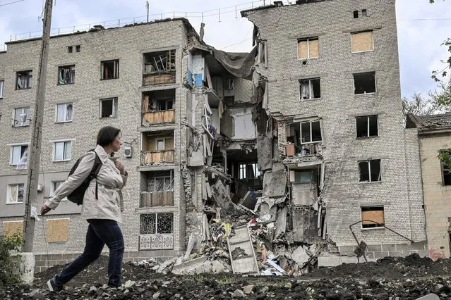 A woman walks by a destroyed apartment building in Bakhmut in the eastern Ukranian region of Donbass on May 22, 2022, amid Russian invasion of Ukraine. (Photo by Aris Messinis/AFP Photo)