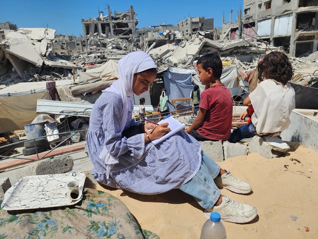 Students do homeworks after the lessons at their tent school, in which their teacher Alaa Abu Mustafa, whose house was destroyed in the Israeli army's attacks, gives them education in Khan Yunis, Gaza on September 03, 2024. The tent school was built on the rubble of the destroyed house of the teacher. Despite the limited and difficult conditions, teacher Alaa strives to ensure that primary school students are not deprived of education. (Photo by Hani Alshaer/Anadolu via Getty Images)