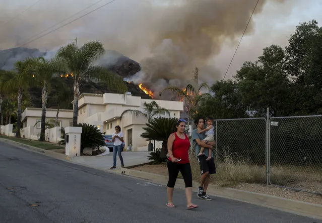 Residents evacuate their home as a wildfire is burning along a hillside in Duarte, Calif., Monday, June 20, 2016. (Photo by Ringo H.W. Chiu/AP Photo)