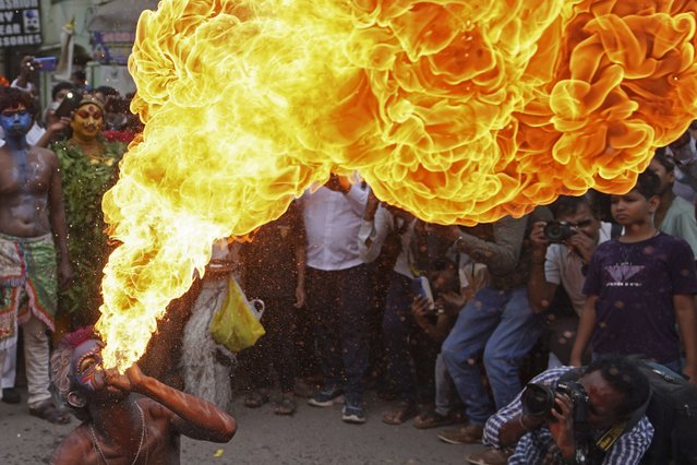 An artist performs a fire stunt during a procession marking “Bonalu” festival in Hyderabad, India, Monday, July 17, 2023. Bonalu is a month-long Hindu folk festival dedicated to Kali, the Hindu goddess of destruction. (Photo by Mahesh Kumar A./AP Photo)