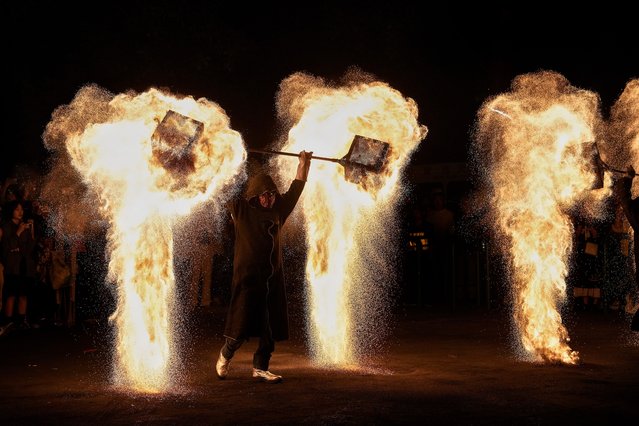 People watch an artist performs a fire kettle show during the Mid-Autumn Festival at a night market in Beijing, Tuesday, September 17, 2024. (Photo by Andy Wong/AP Photo)