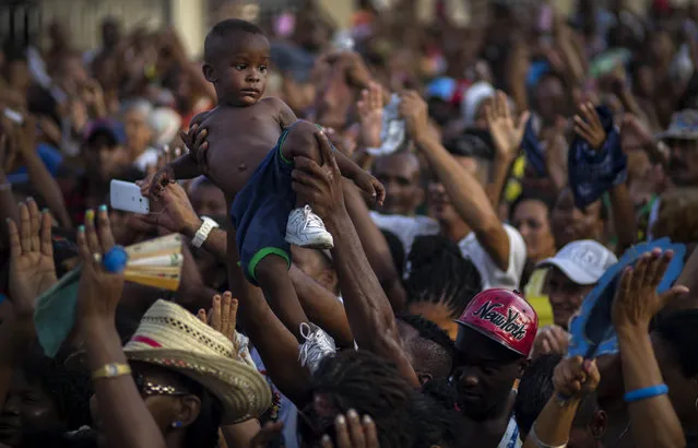 In this July 27, 2015 photo, a child is raised above the crowd at a concert by Cuban singer Candido Fabre during carnival celebrations in Santiago, Cuba. The city of Santiago de Cuba saw less than a tenth of the tourist traffic of Havana last year amid large-scale government investment in rehabbing the city for its 500th anniversary this summer. (Photo by Ramon Espinosa/AP Photo)