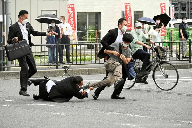 This image received from the Asahi Shimbun newspaper shows a man (centre R) suspected of shooting former Japanese prime minister Shinzo Abe being tackled to the ground by police at Yamato Saidaiji Station in the city of Nara on July 8, 2022. Abe was pronounced dead on July 8, the hospital treating him confirmed, after he was shot at a campaign event in the city of Nara. (Photo by Asahi Shimbun/AFP Photo)
