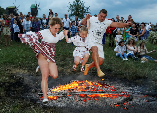 People jump over a campfire during a celebration on the traditional Ivana Kupala (Ivan the Bather) holiday, the ancient tradition, originating from pagan times, is usually marked with grand overnight festivities during which people sing and dance around campfires, believing it will purge them of their sins and make them healthier, in Kiev, Ukraine, July 6, 2016. (Photo by Gleb Garanich/Reuters)