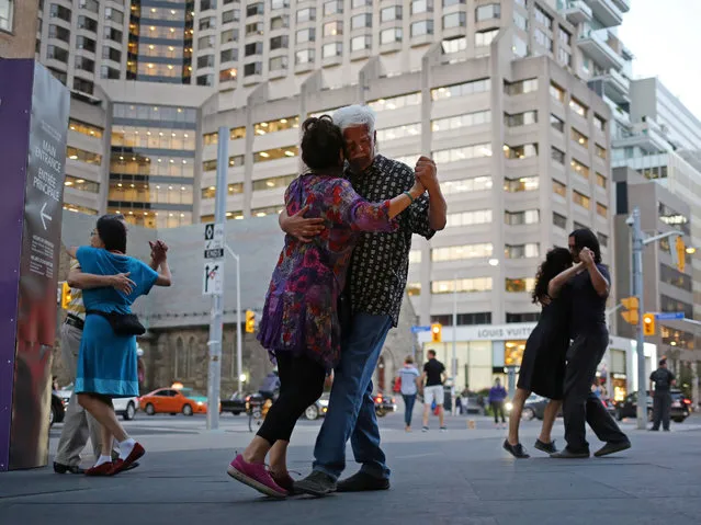 Couples dance the tango during an informal event called Milonga Arrabalera, held fortnightly throughout the summer outside the Royal Ontario Museum in Toronto, Ontario, Canada on August 17, 2017. (Photo by Chris Helgren/Reuters)