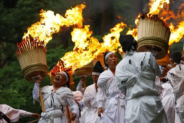 White-robed men hold up flaming torches during an annual fire festival at the World Heritage-listed Kumano Nachi Taisha shrine in the Wakayama Prefecture town of Nachikatsuura, western Japan on July 14, 2022. (Photo by Kyodo News/Newscom/Avalon)