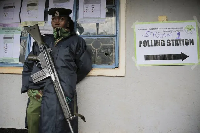 A Kenyan officer stands guard at a polling station in Sugoi, 50 kms (35 miles) north west of Eldoret, Kenya, Tuesday August 9, 2022. Kenyans are voting to choose between opposition leader Raila Odinga Deputy President William Ruto to succeed President Uhuru Kenyatta after a decade in power. (Photo by Brian Inganga/AP Photo)