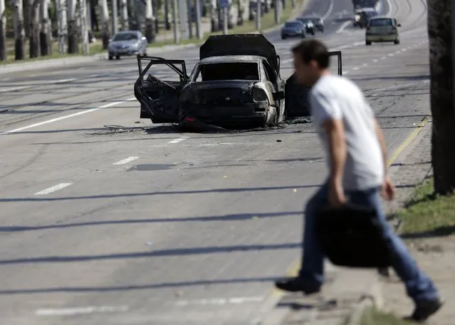 A man crosses a street near a burned car in central Donetsk on August 16, 2014. Washington on Friday urged Moscow to stop its “extremely dangerous and provocative” activities after Ukraine said it had destroyed part of a Russian military convoy that entered its territory. (Photo by Max Vetrov/AFP Photo)