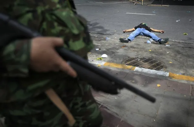 Thai soldiers storm into anti-government protesters' encampment while a protester lies dead on Wednesday May 19, 2010, in Bangkok, Thailand. (Photo by Wong Maye-E/AP Photo)