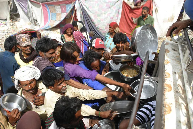 People confined in their homes due to lockdown to contain the coronavirus outbreak jostle to receive free food, in Hyderabad, Pakistan, Wednesday, March 25, 2020. (Photo by Pervez Masih/AP Photo)