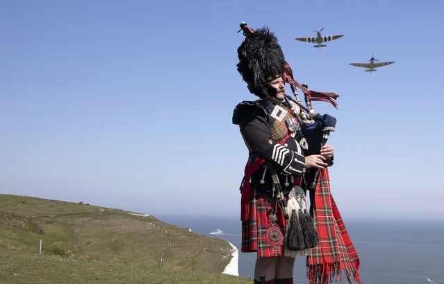 Pipe major Andy Reid of The Scots Guards plays his pipes on the cliffs of Dover, Kent, as two Spitfires from the Battle of Britain memorial flight fly overhead, ahead of commemorations to mark the 75th anniversary of VE Day Friday May 8, 2020. (Photo by Richard Pohle/The Times via AP Photo)