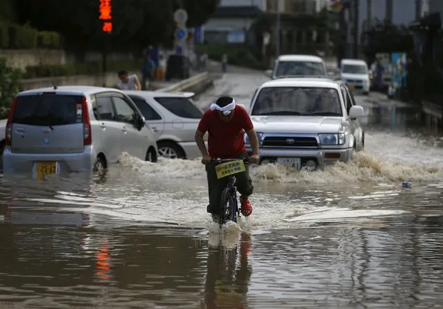 A local resident rides a bicycle through a residential area flooded by the Kinugawa river, caused by typhoon Etau, in Joso, Ibaraki prefecture, Japan, September 12, 2015. (Photo by Issei Kato/Reuters)