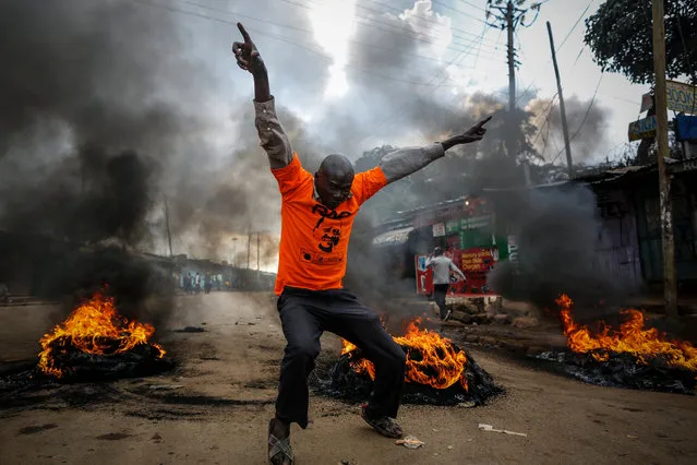 A supporter of the opposition coalition the National Super Alliance (NASA) and its presidential candidate Raila Odinga reacts in front of a burning barricade he and others set up to block vehicles from delivering electoral materials to the polling stations in ther areas in Kibera slum, one of the opposition strongholds in Nairobi, Kenya, 25 October 2017. The case filed by activists to postpone the October 26 repeat poll failed at the Supreme Court on 25 October, due to lack of quorum. Supporters of Odinga, who has said he would not participate in the repeat poll, are urged to biycott and stay away from the polling stations on voting day. (Photo by Dai Kurokawa/EPA/EFE)