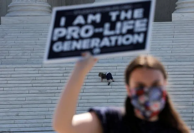 A child plays on the steps of the U.S. Supreme Court building as an anti-abortion activist holds a sign during a demonstration outside the court in Washington, U.S., June 29, 2020. The child was being photographed by a parent (not shown) at the same time demonstrators gathered outside the court. (Photo by Carlos Barria/Reuters)